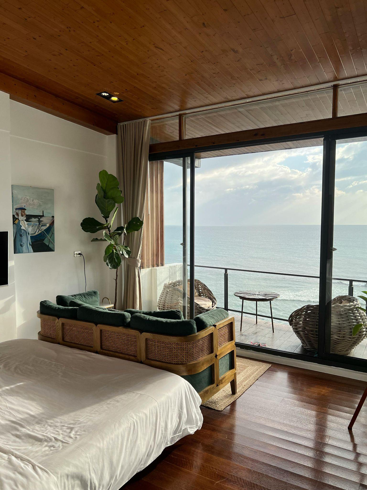 Bedroom opening to a balcony with glass railing and ocean view.